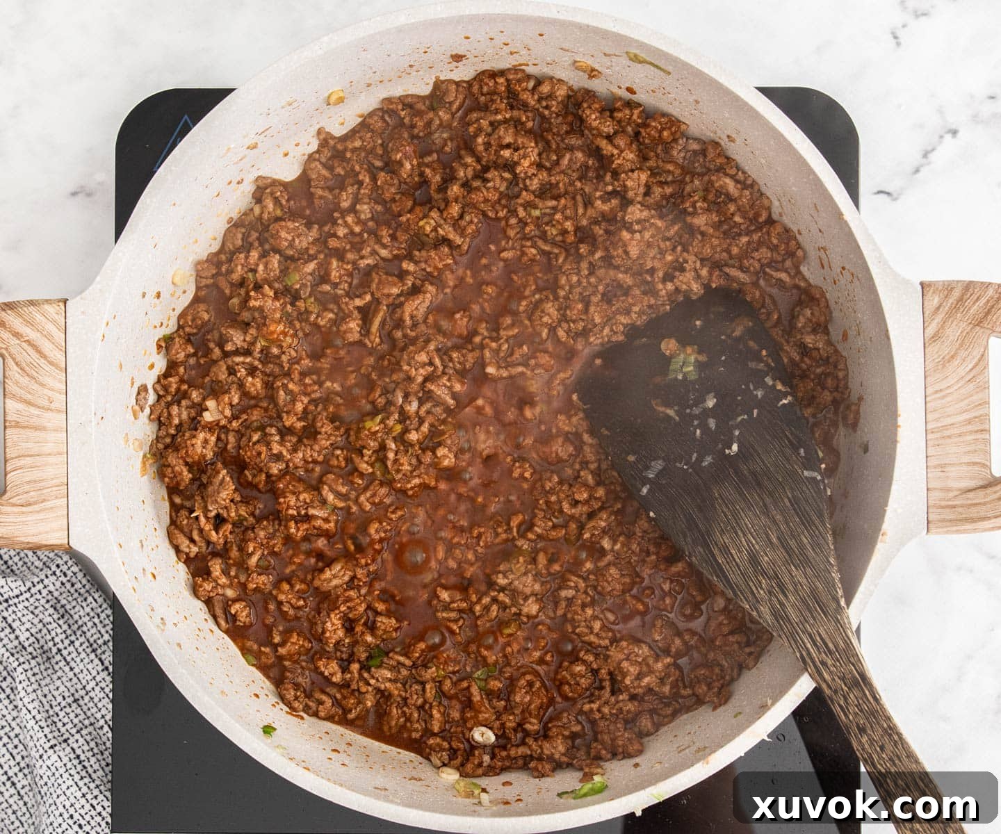 The beef with the sauce added, bubbling in a pan.