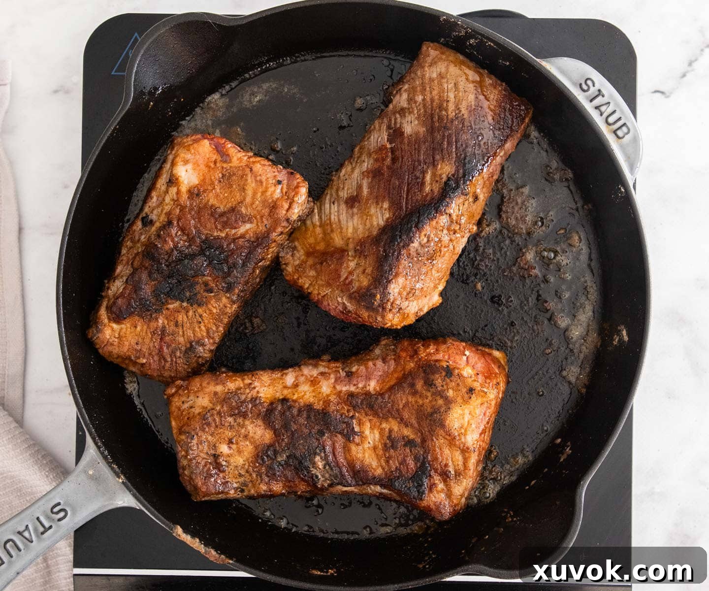 Close-up shot of beef chunks being browned in a hot skillet, showcasing the delicious sear forming on the meat.