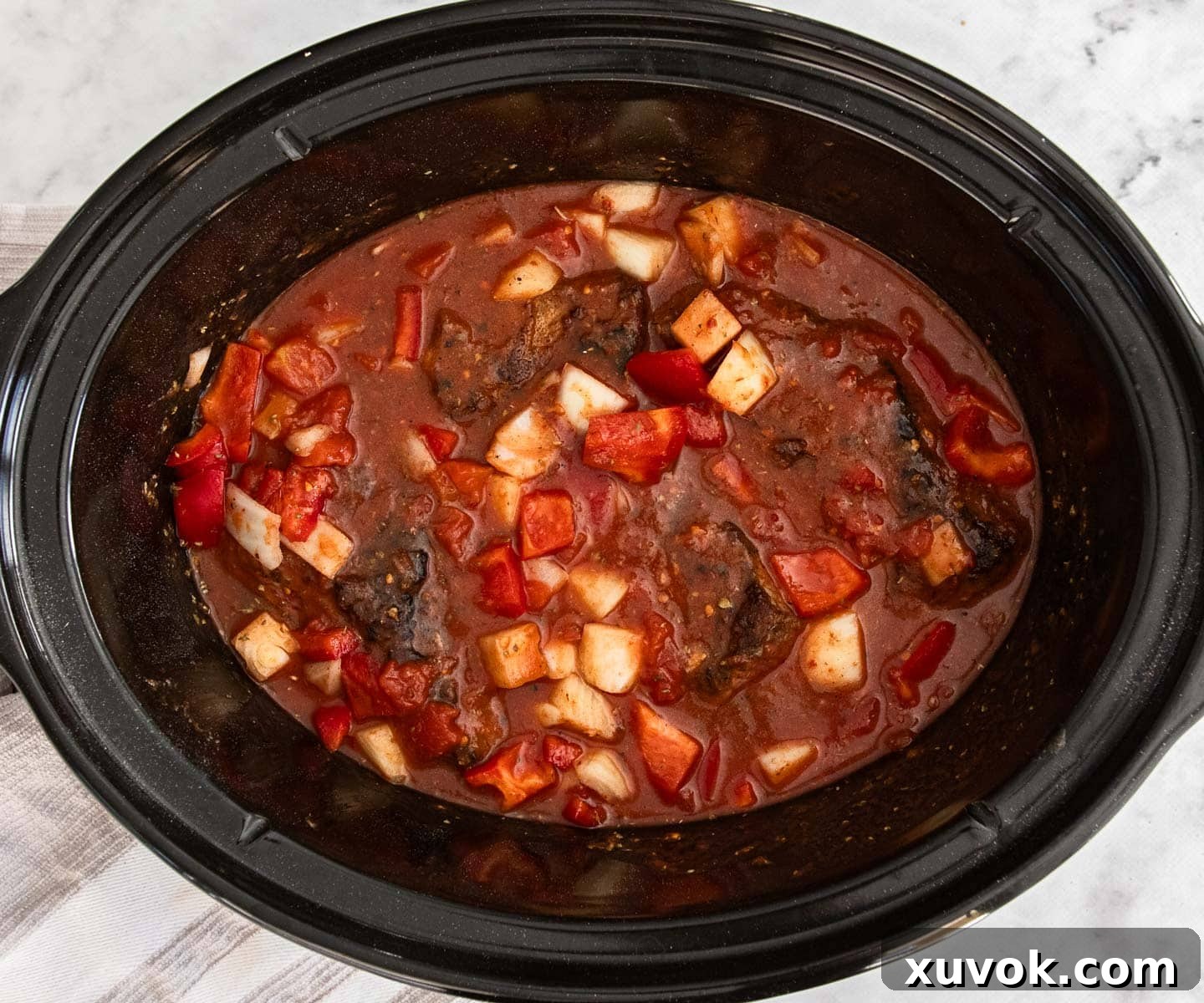 All the slow cooker chilli con carne ingredients neatly arranged in the slow cooker pot, ready for cooking.