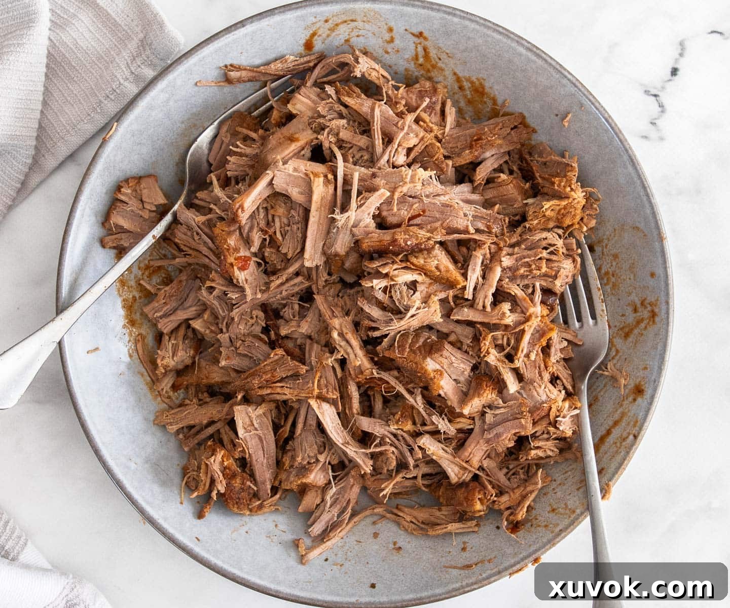 Fork shredding tender brisket in a bowl, illustrating the perfect texture achieved by slow cooking.