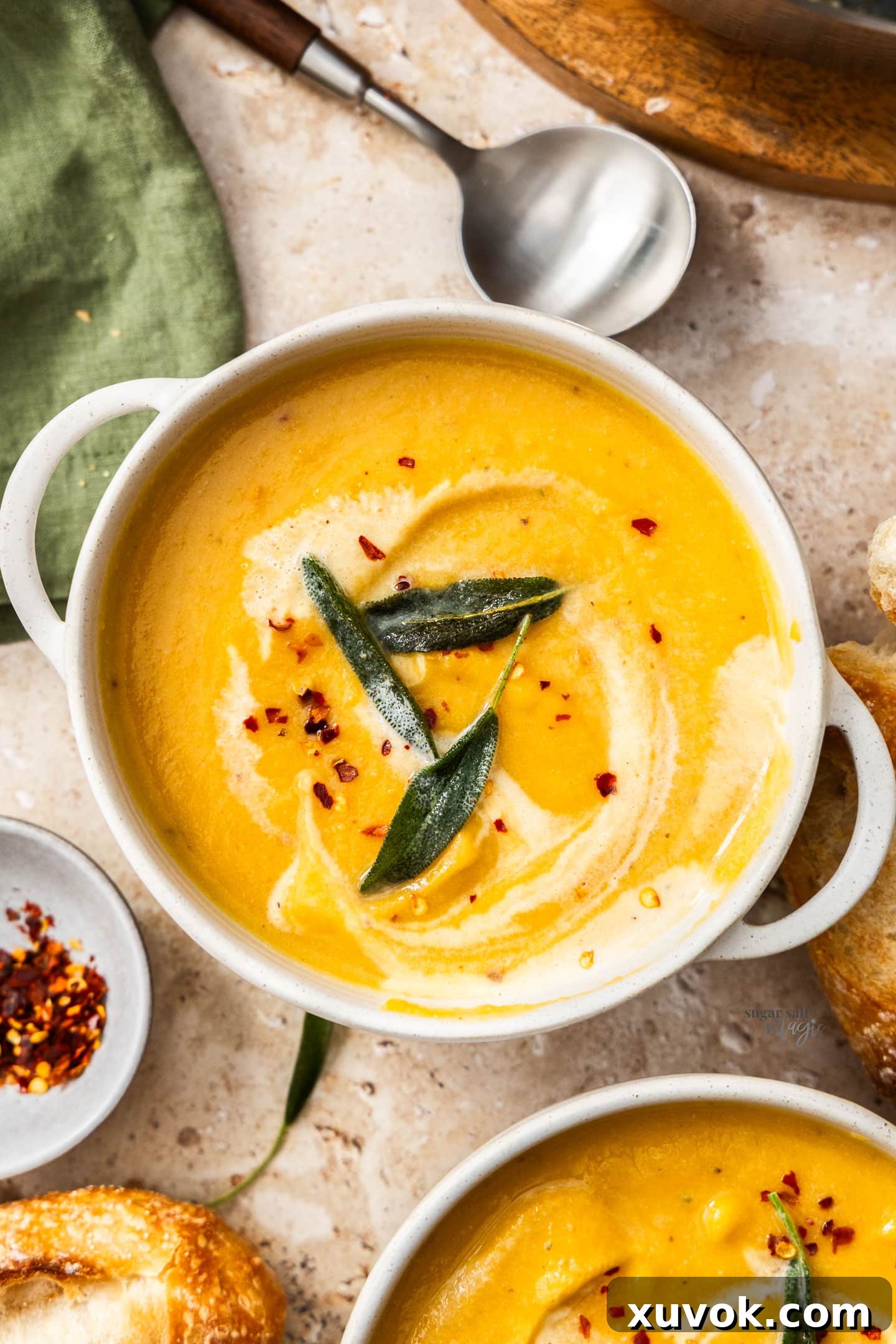 Top down view of a bowl of creamy roasted cauliflower and pumpkin soup, garnished with fresh herbs.
