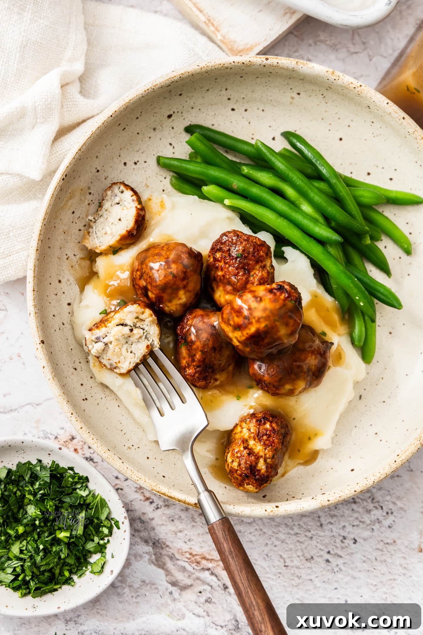 Chicken meatballs with gravy and mashed potatoes in a plate, top down view.