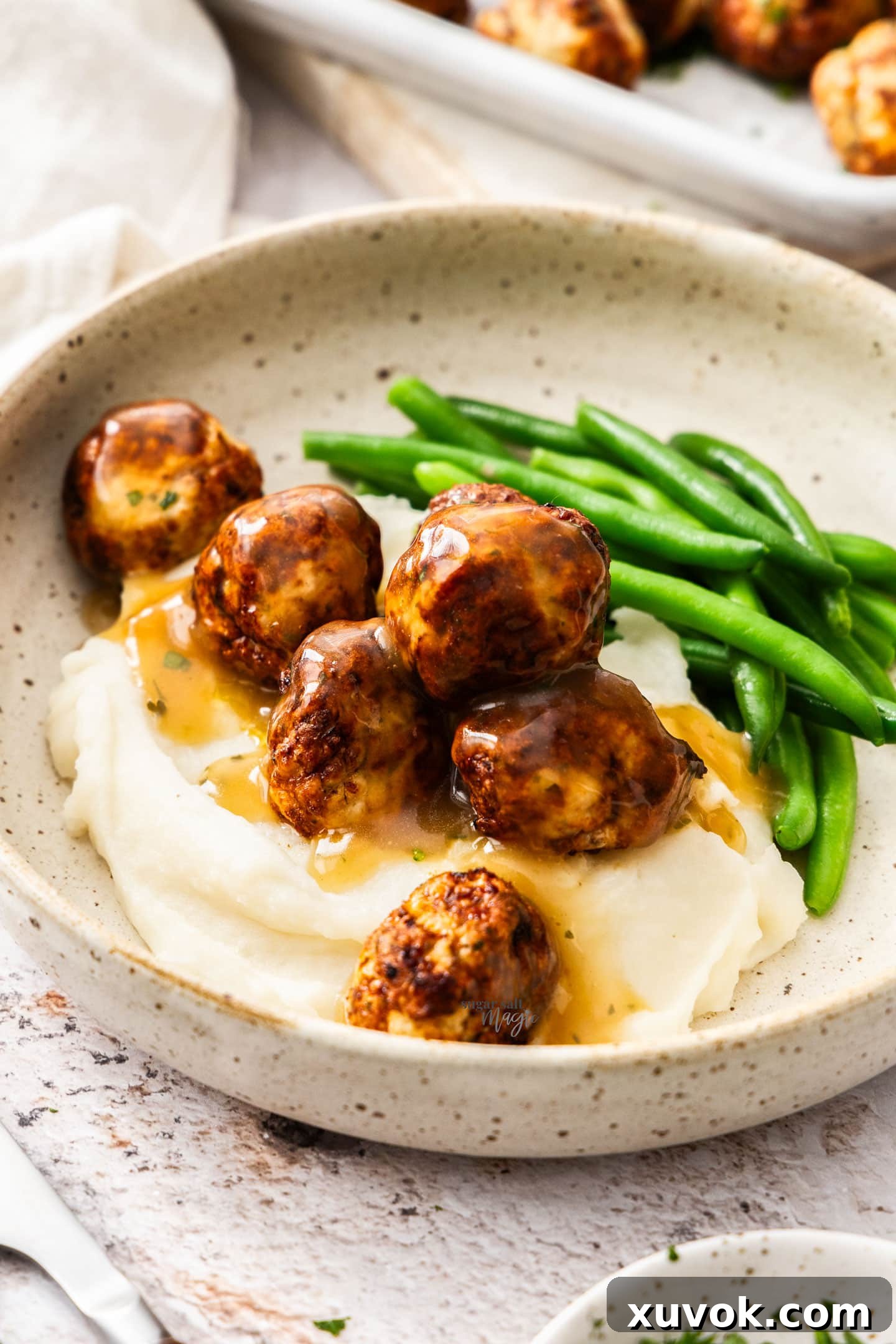 Chicken meatballs with gravy and mashed potatoes on a plate.