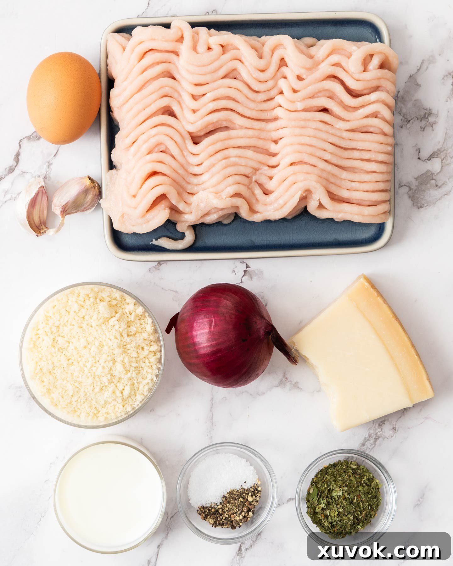 Ingredients for chicken meatballs on a marble surface.