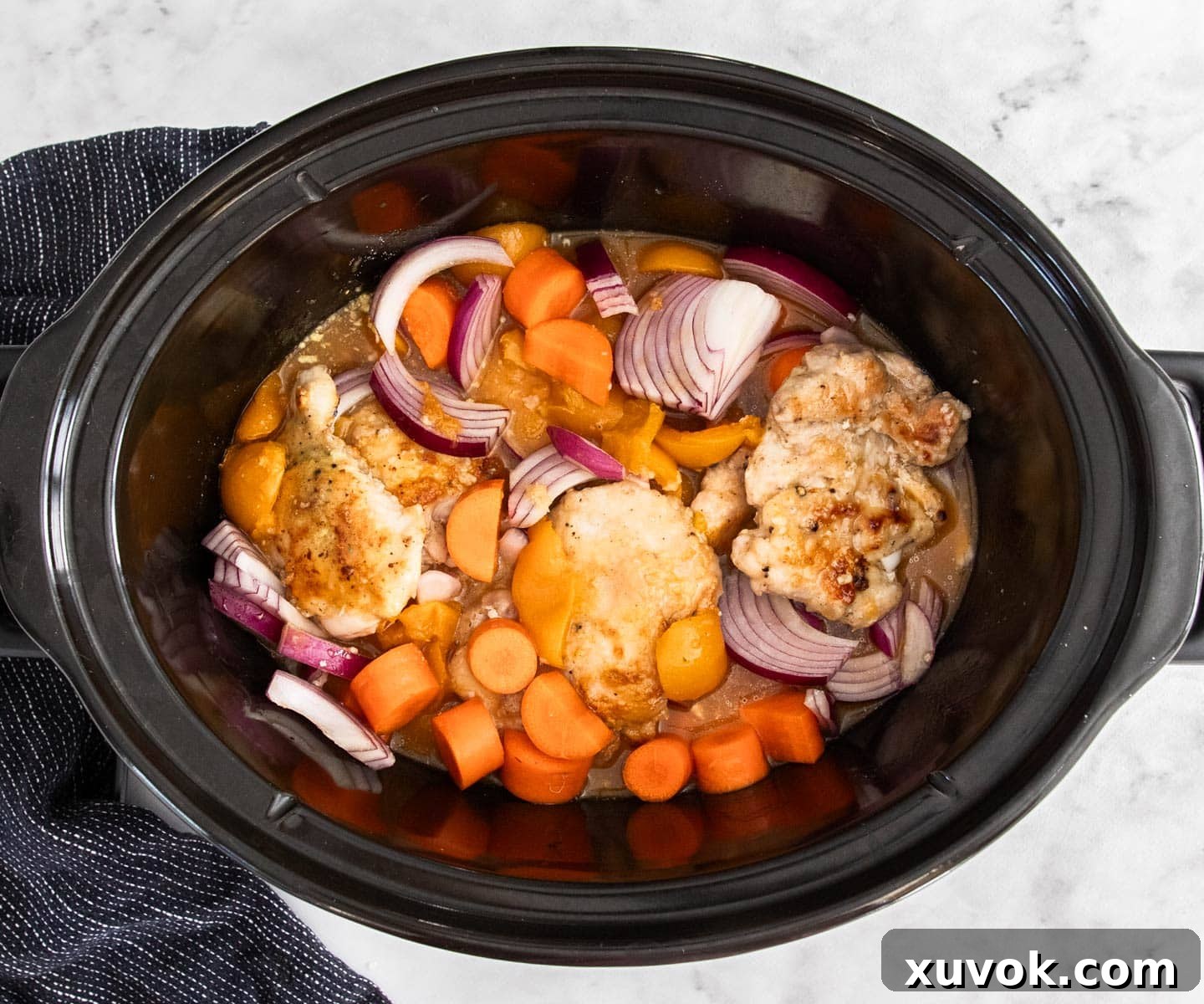 All the ingredients for slow cooker apricot chicken combined in a slow cooker bowl, ready to cook.