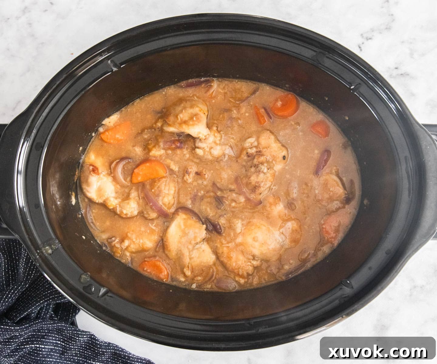 The slow cooker apricot chicken in the slow cooker, ready for the final addition of beans and mushrooms.