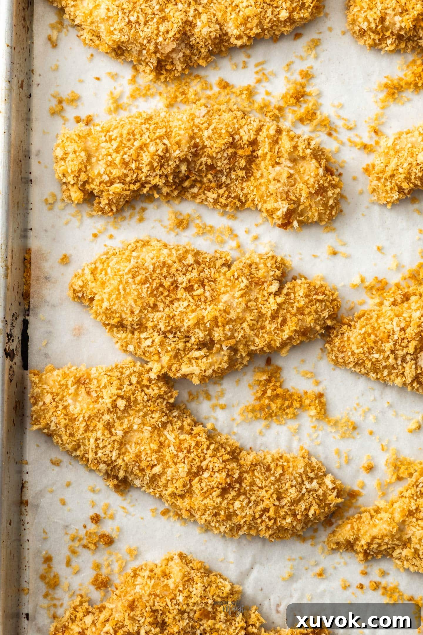 Top down view of 9 crunchy chicken tenders on a baking sheet.