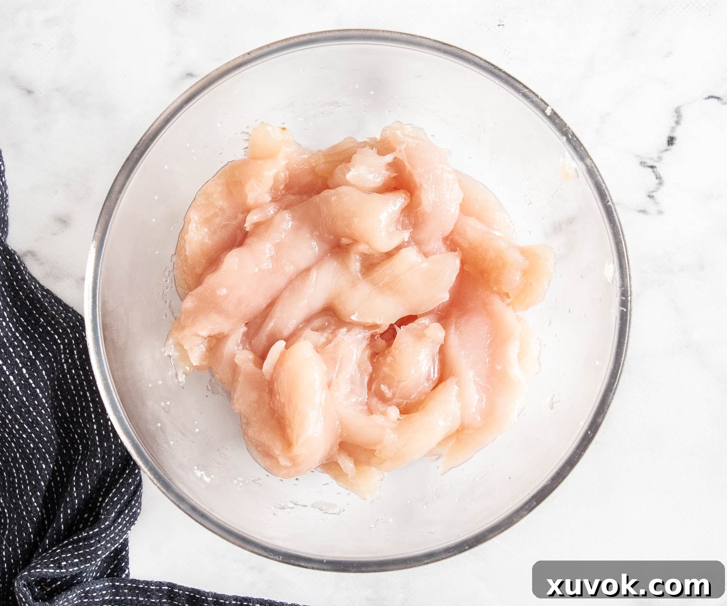 Chicken tenders, brined, in a glass bowl.
