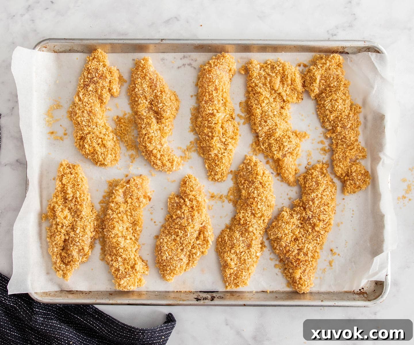 A batch of chicken tenders on a baking sheet ready to bake.
