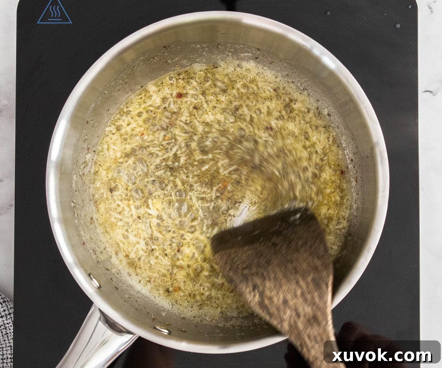The minced garlic and butter being stirred together in a pan, releasing their aroma.