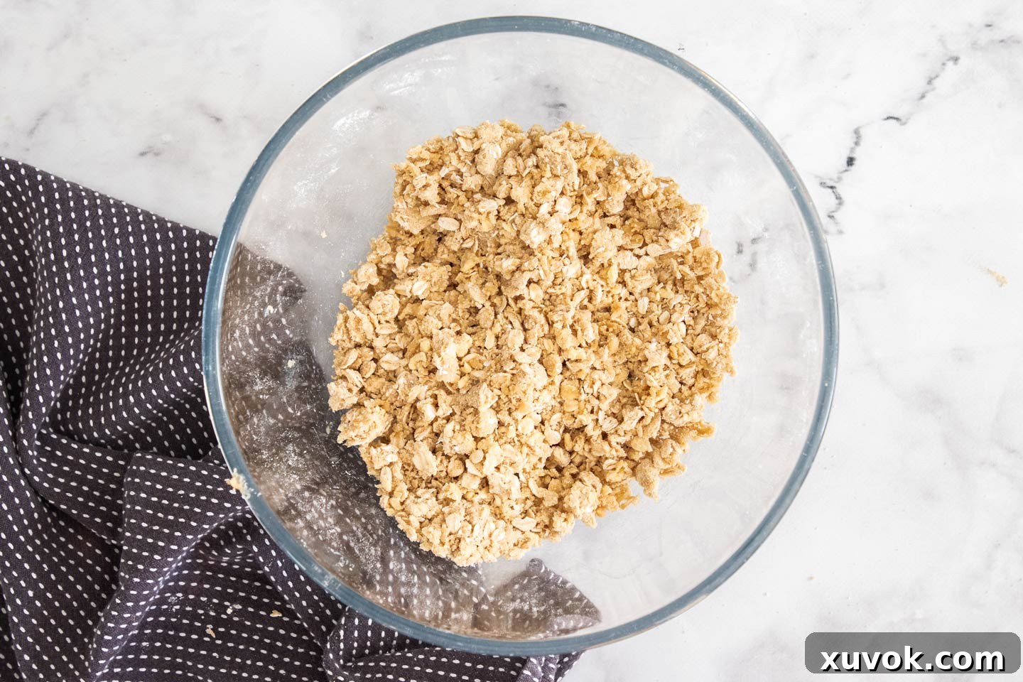 A close-up view of the crumble topping mixture in a bowl, showcasing its perfectly crumbly texture after butter has been incorporated.