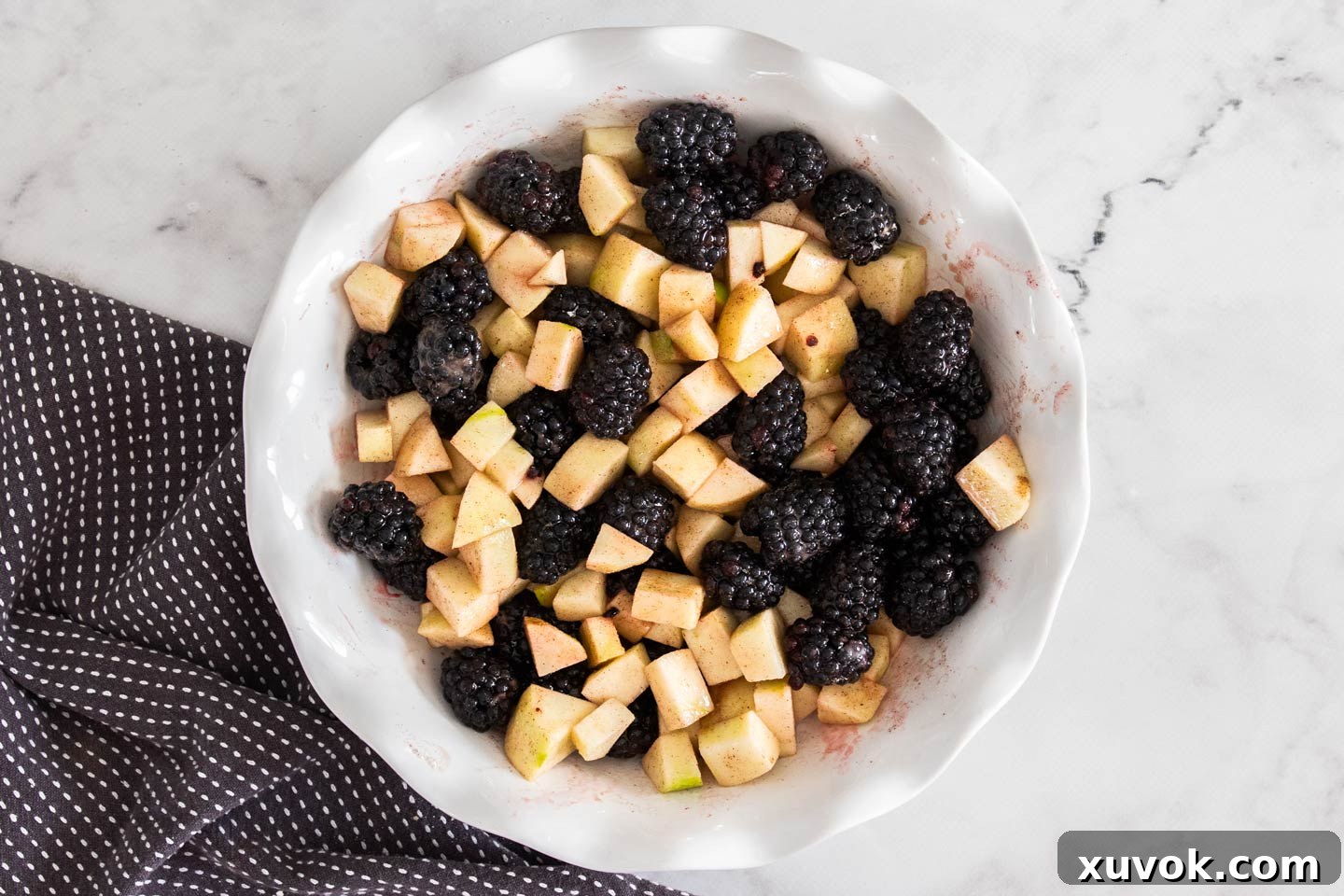 Freshly chopped apples and juicy blackberries mixed together in a pie dish, ready for the crumble topping.