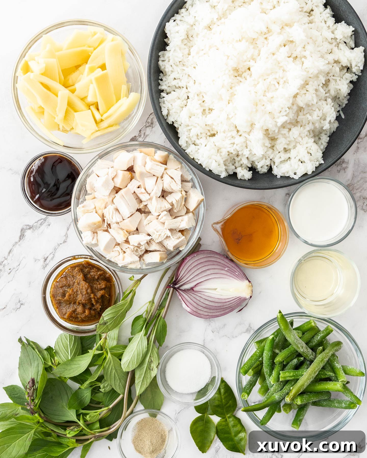 A flat lay photograph showcasing all the fresh ingredients for Thai green curry fried rice artfully arranged on a clean marble countertop, ready for preparation.