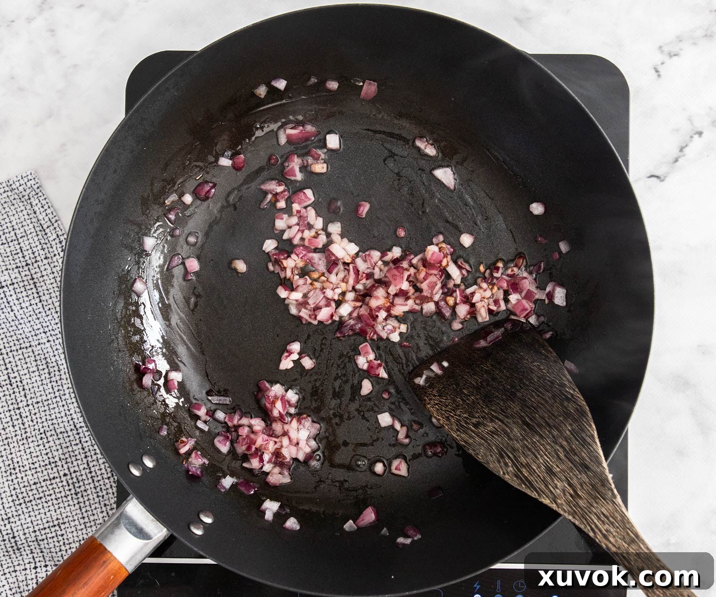 Diced purple onion frying in a hot wok, gently softening and becoming translucent.