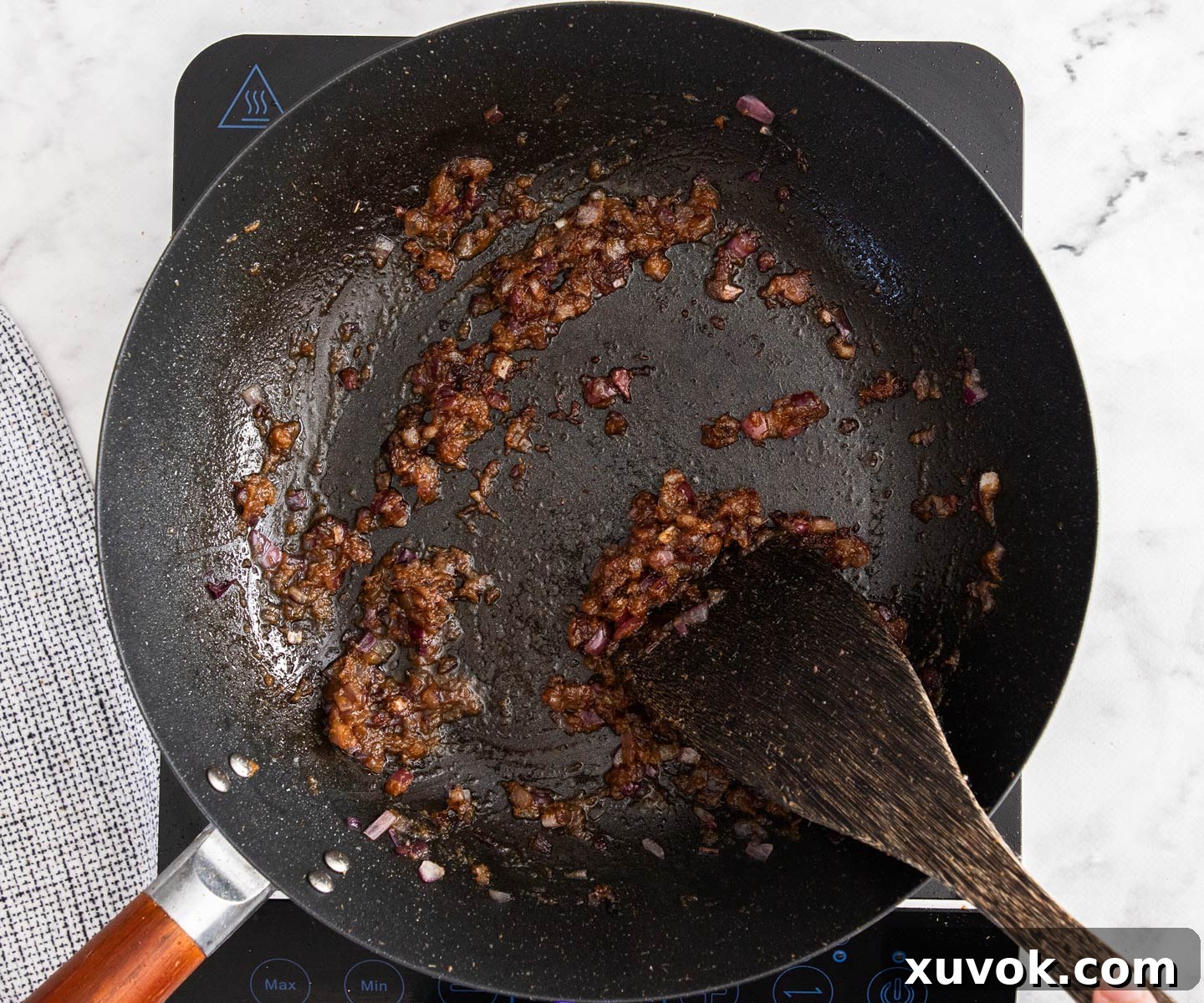 The aromatic green curry paste sizzling and cooking in the wok alongside the onions, deepening in color and fragrance.