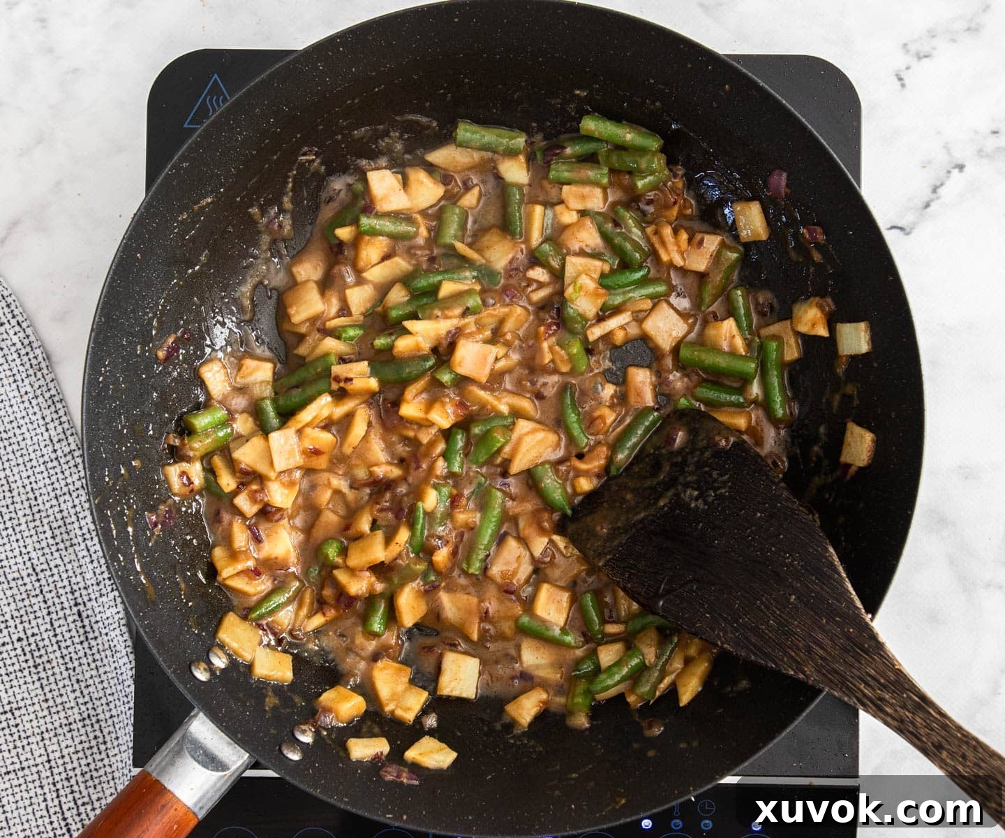 A mix of vibrant vegetables and creamy coconut sauce added to the wok, simmering gently to combine flavours.