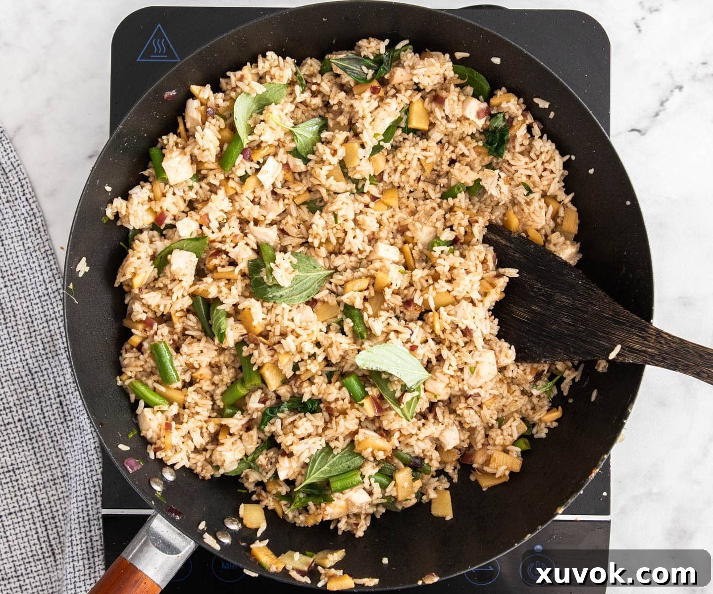 A top-down view of the delicious Thai green curry fried rice with chicken, actively cooking and mixing in a large wok.
