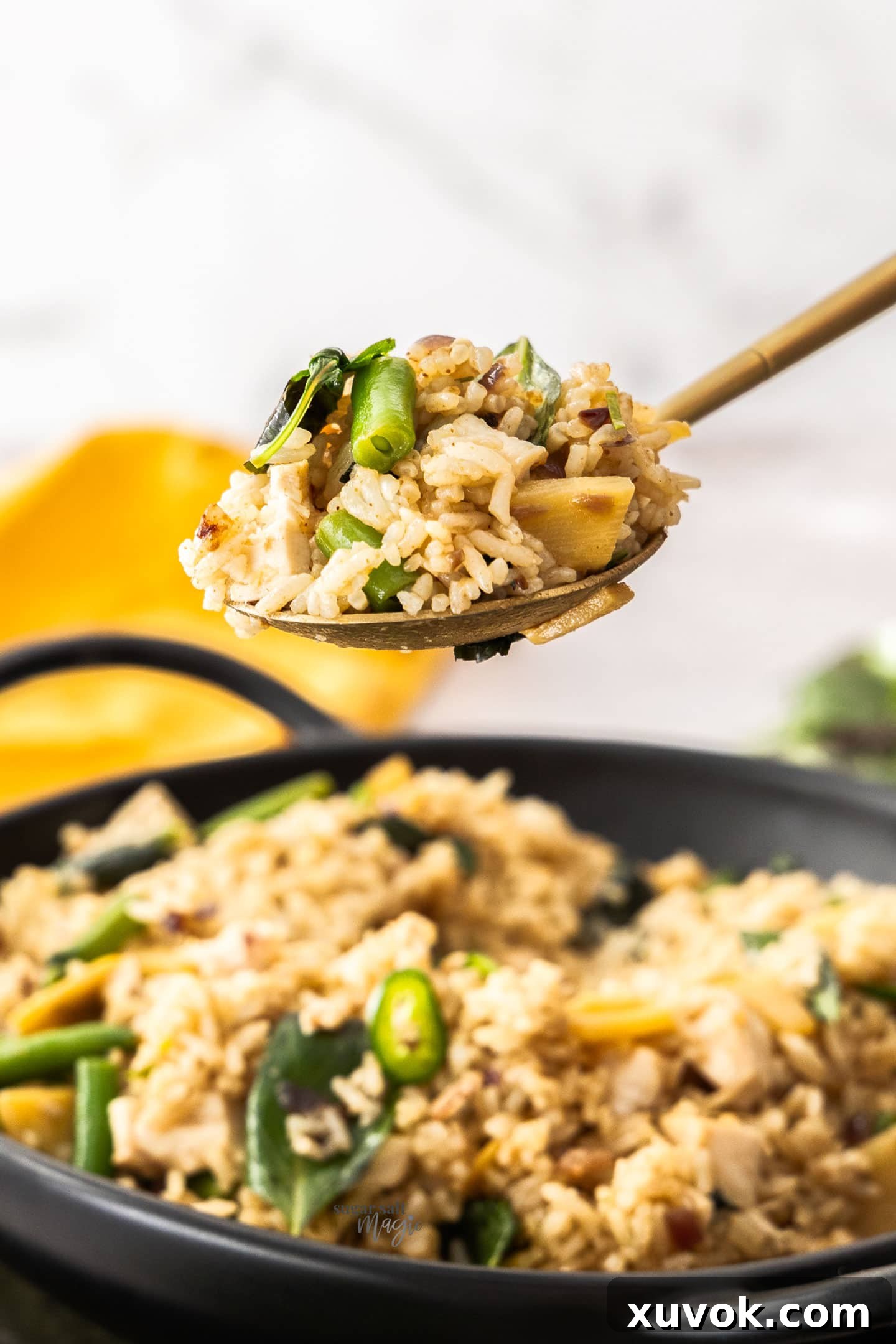 A close-up shot of a spoon scooping up delicious Thai green curry fried rice, showcasing its vibrant colors and inviting texture.