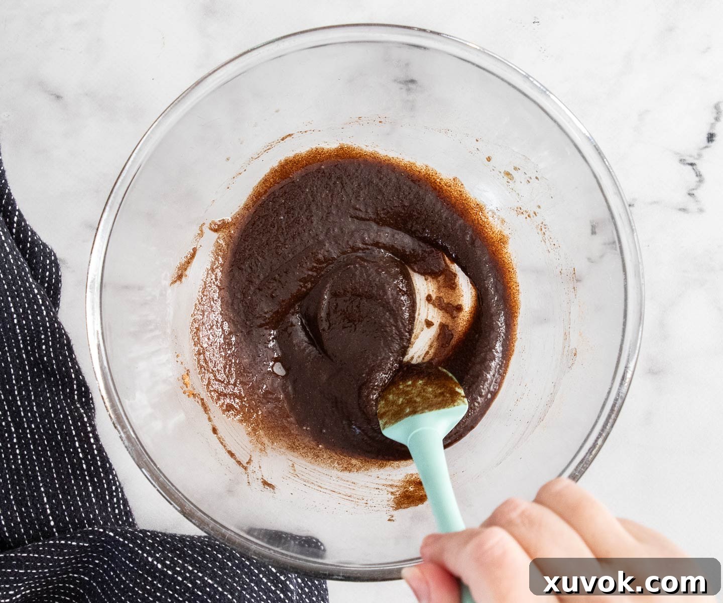 Melted butter, brown sugar, and ground cinnamon being stirred together in a small bowl to create the pastry filling.