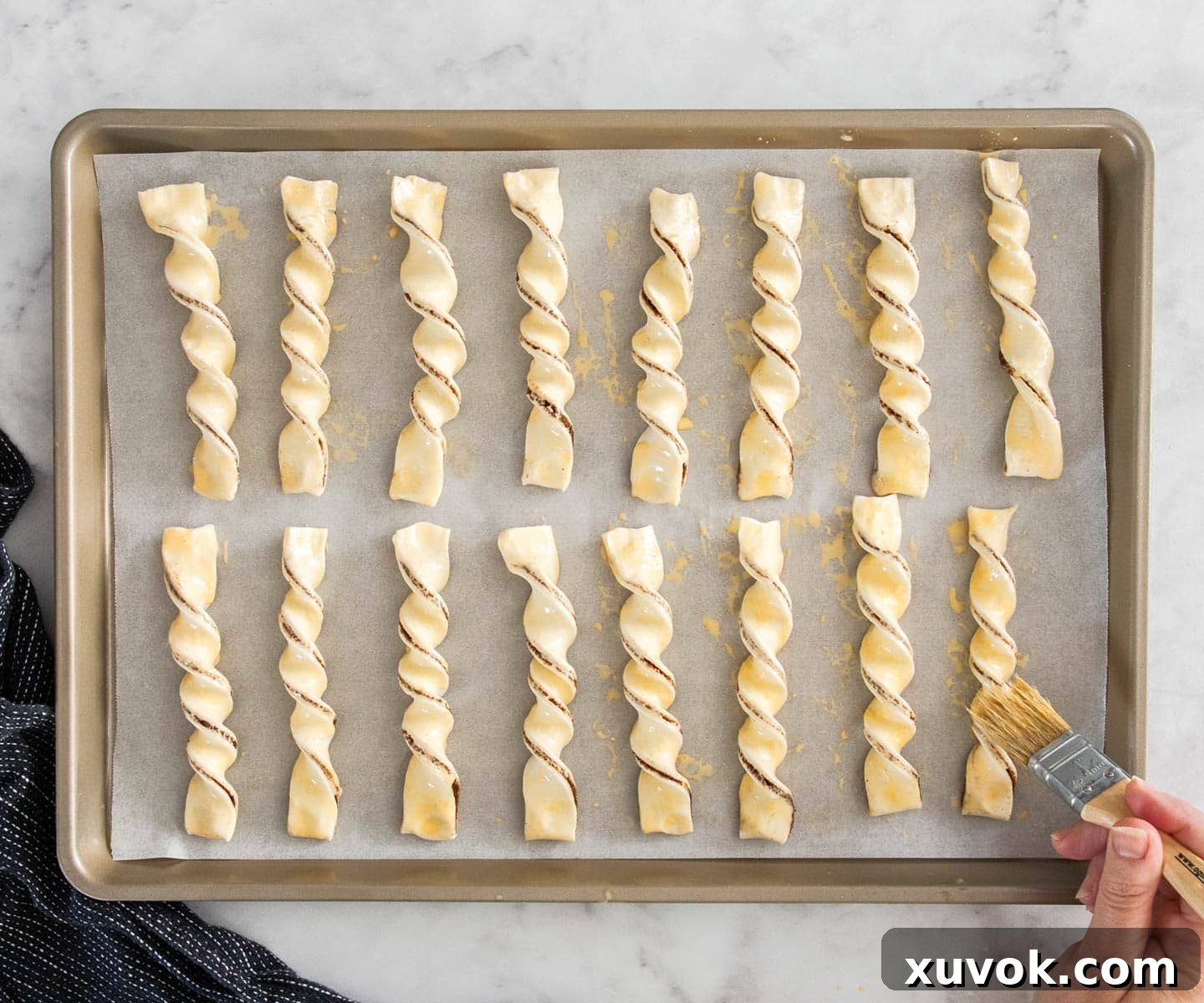 Raw cinnamon puff pastries arranged neatly on a baking tray, ready for the oven.