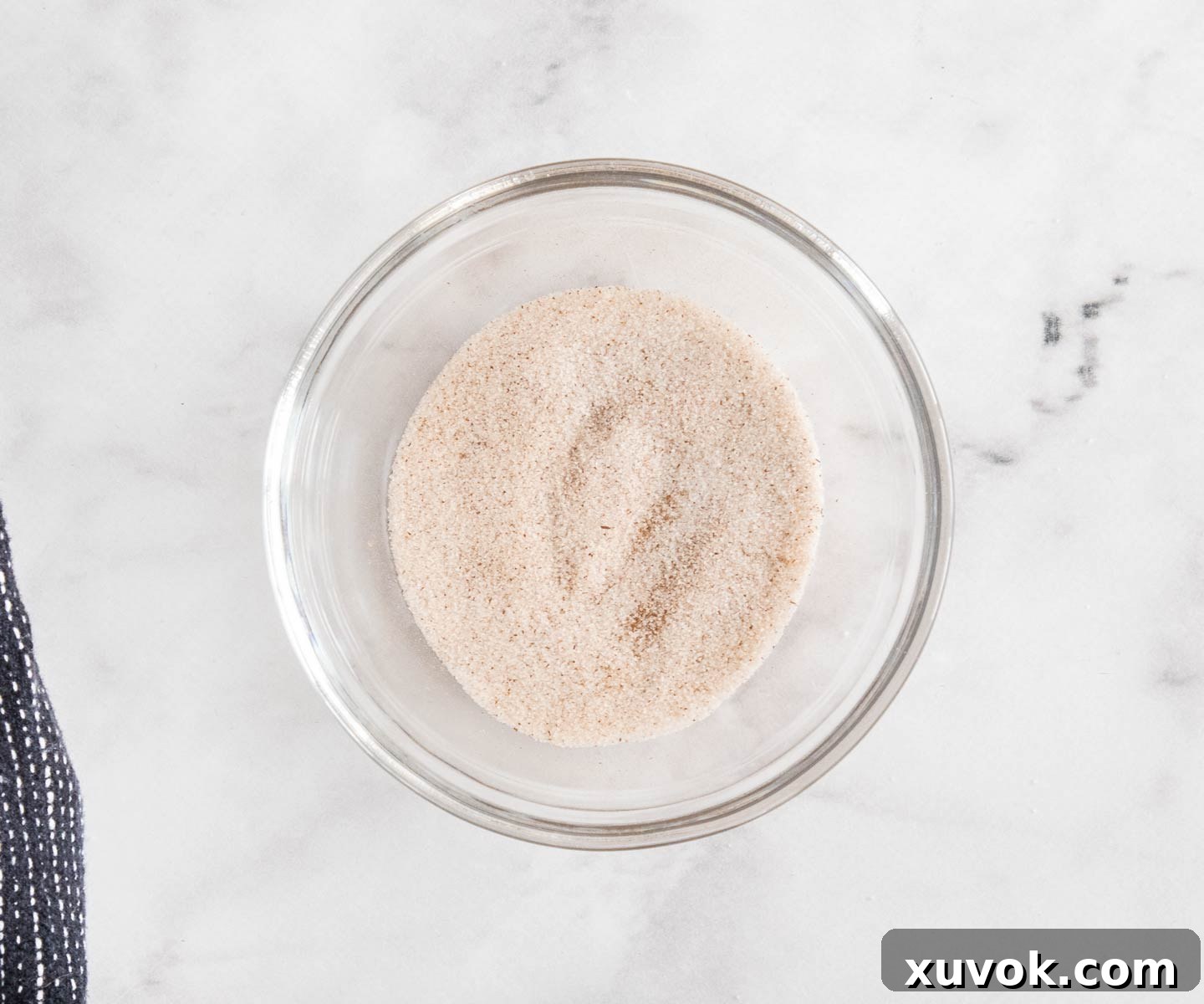 Cinnamon sugar mixture in a small glass bowl, ready for dusting the baked pastries.