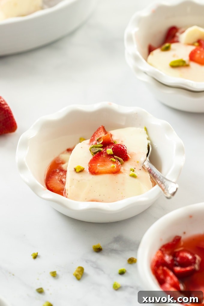 A white dish filled with panna cotta, generously topped with macerated strawberries.