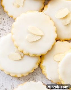 Top down view of almonds cookies topped with icing and sliced almonds.