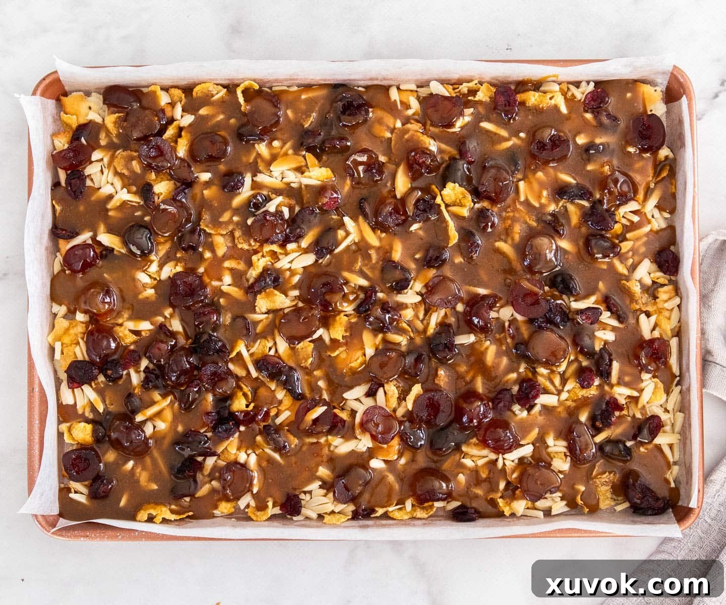 The hot toffee mixture carefully poured over the layered ingredients in the baking tray, ready for baking.