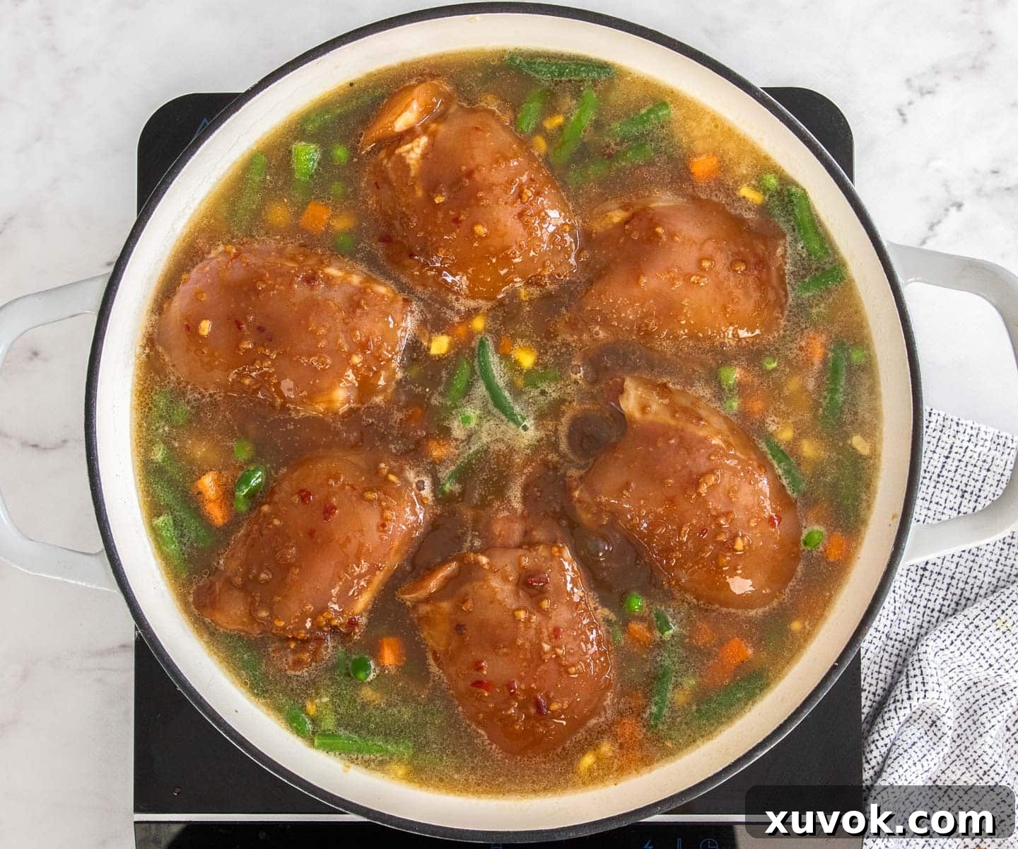 The raw chicken thighs nestled into the rice and stock.