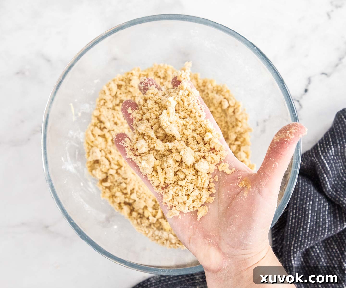 A hand holding some of the crumble filling to show the texture.