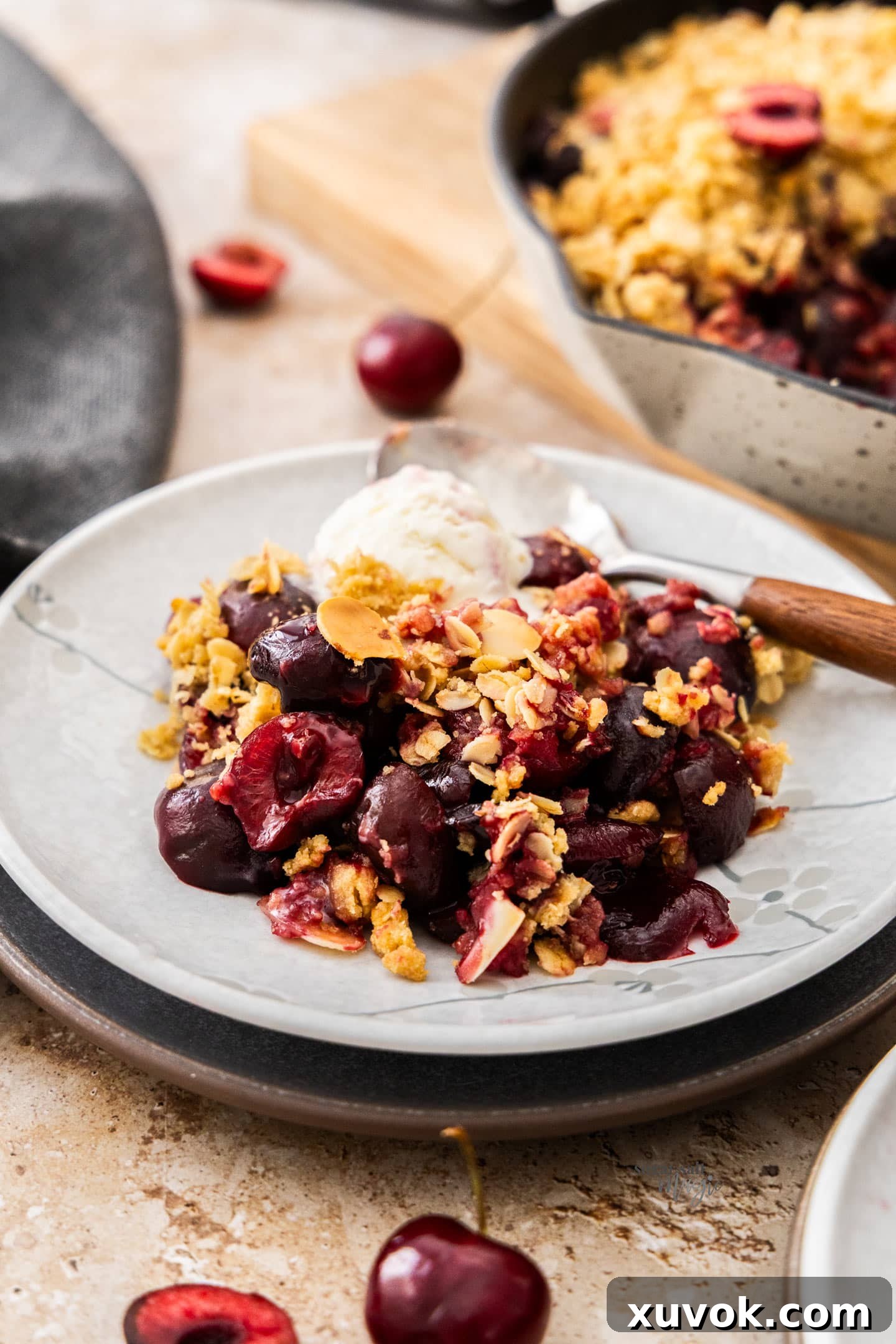 A scoop of cherry crumble on a dessert plate with some ice cream.