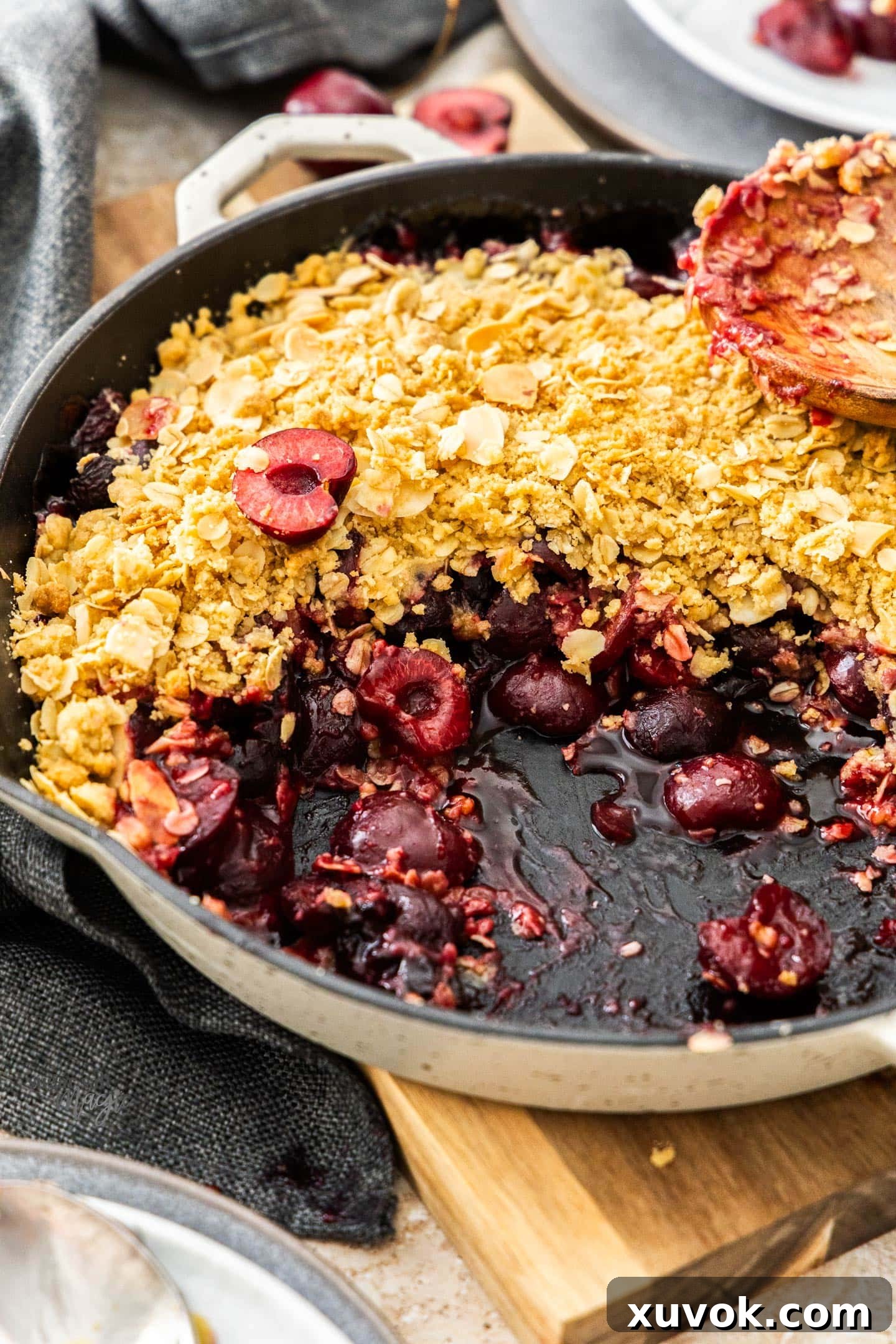 Baked cherry crumble in a skillet on a wooden board.