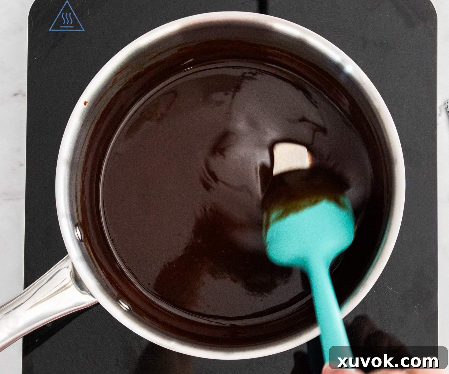 Stirring melted butter and dark chocolate in a saucepan, a crucial first step for fudgy brownies.