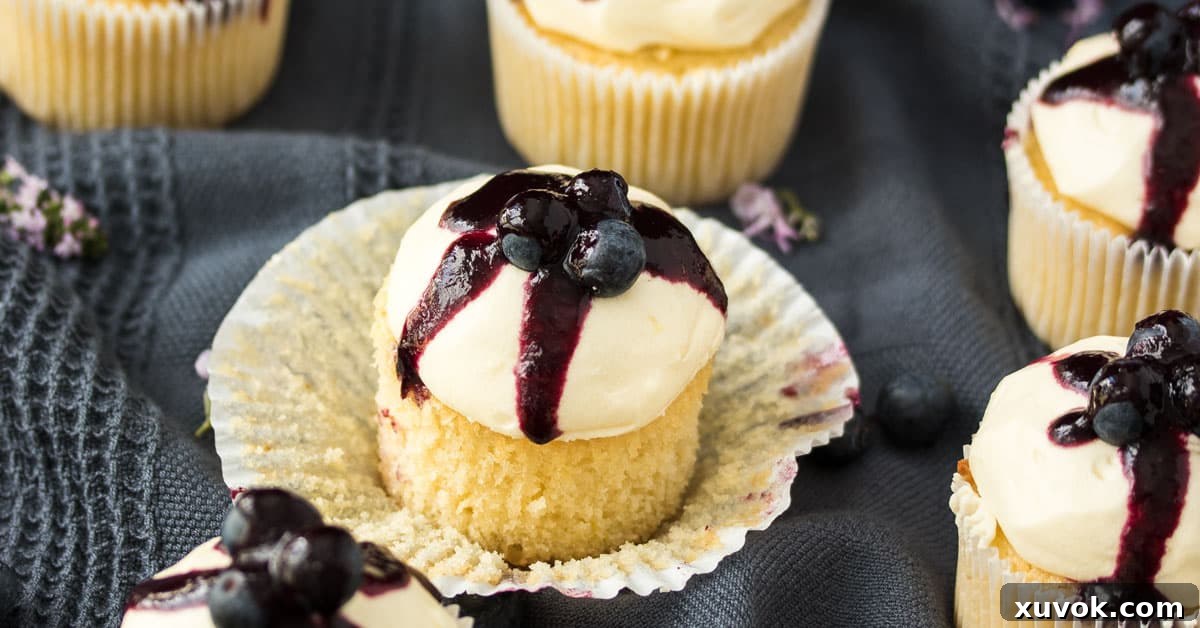 A beautifully decorated Lemon Blueberry Cupcake with its paper peeled off, ready to be enjoyed.