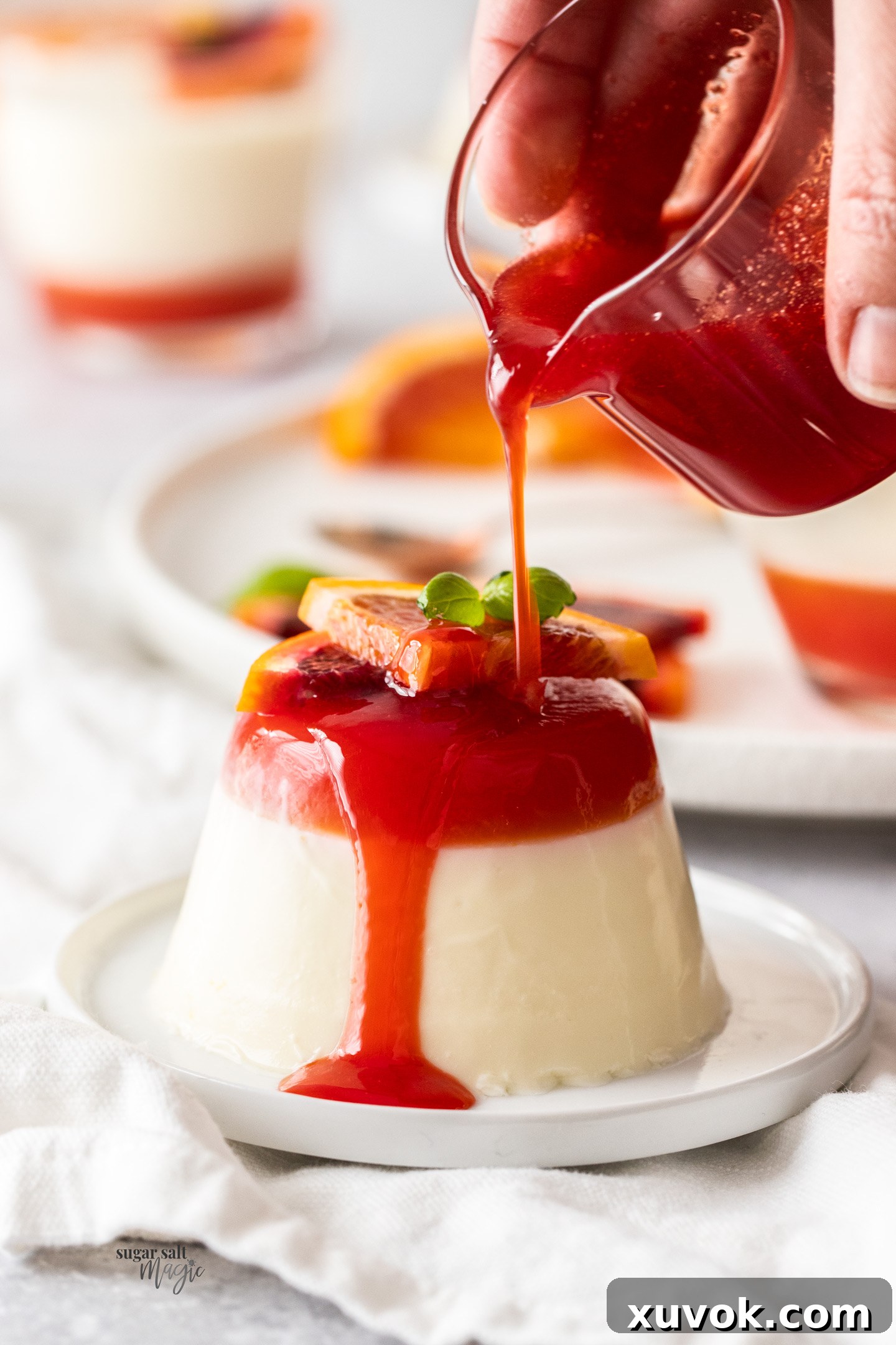 Blood orange syrup being poured over a buttermilk panna cotta.