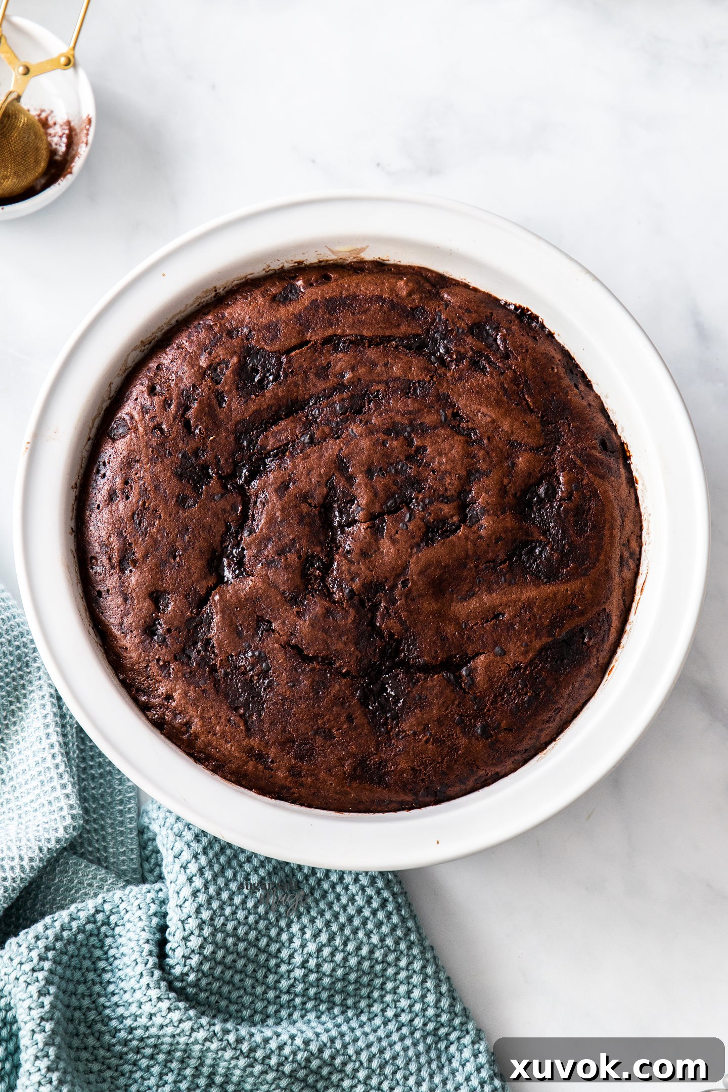 Top down view of a warm, baked chocolate self-saucing pudding in a pie dish, showcasing its glistening, rich chocolate sauce and tender cake.