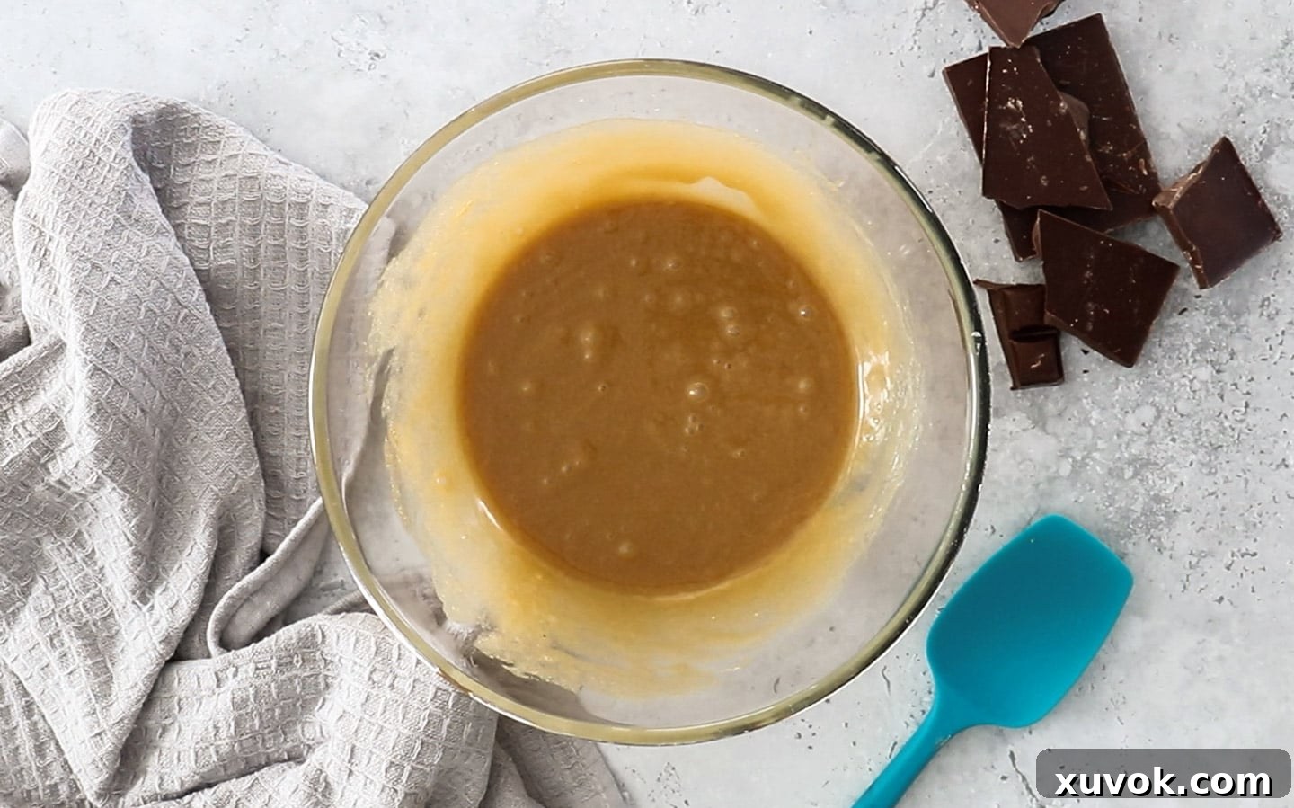 A bowl showing the perfectly combined mixture of eggs, melted butter, and sugars, creating a smooth and creamy wet base for the chocolate cupcakes.