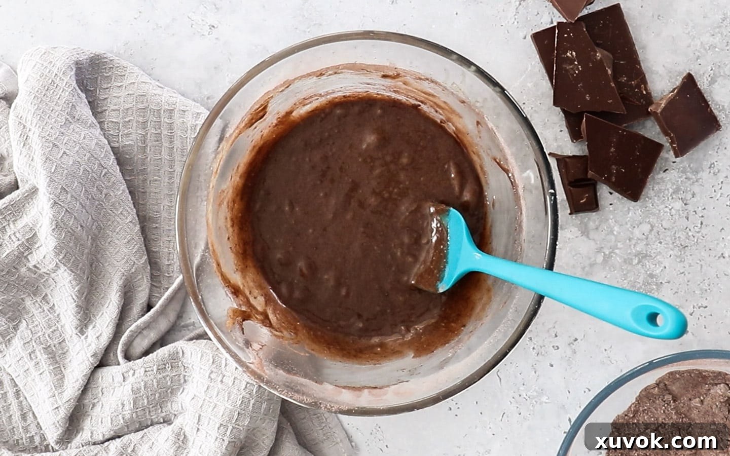 Chocolate cupcake batter in a mixing bowl after the initial addition of dry ingredients, showing its thick and rich texture.