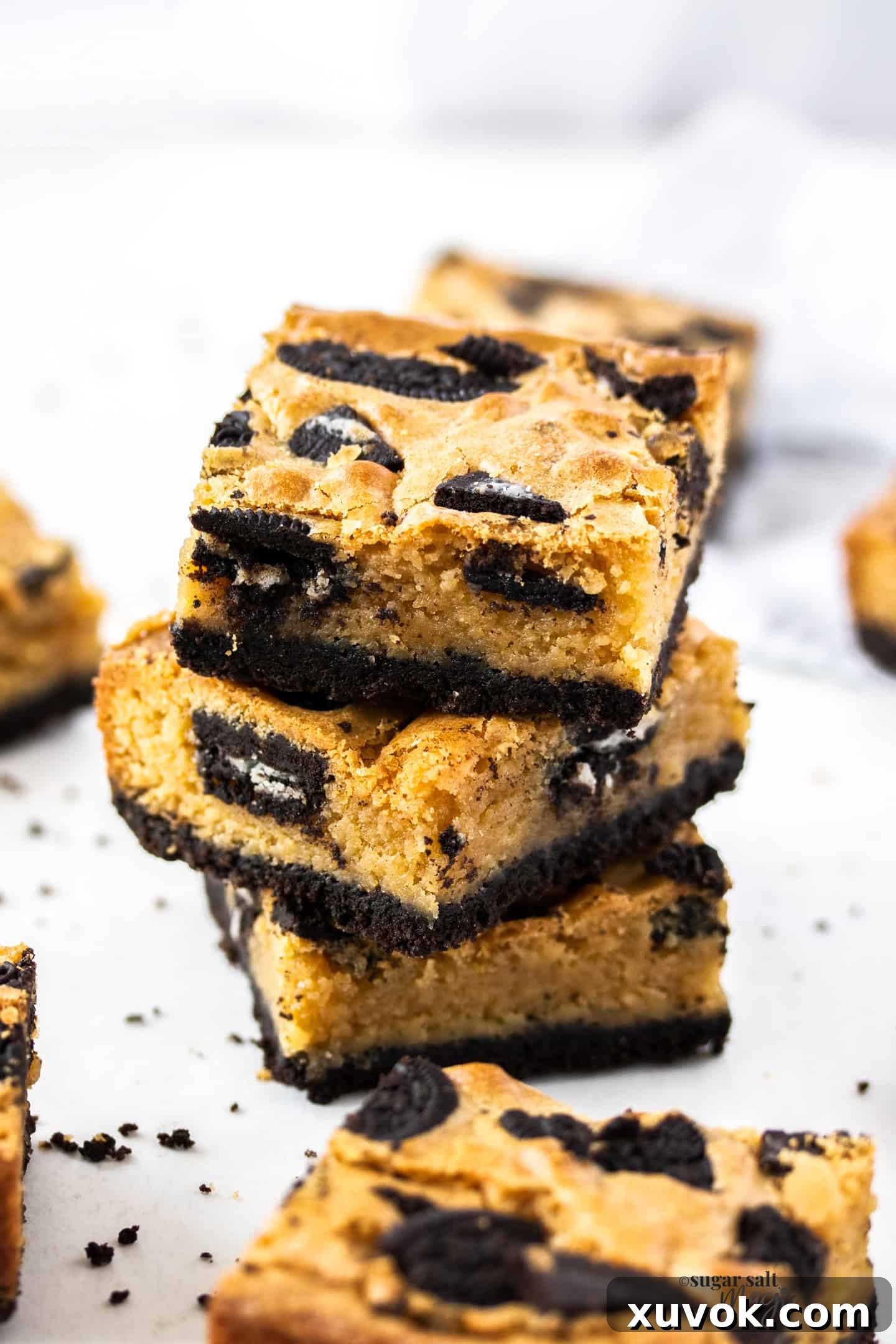 A stack of three perfectly baked Oreo blondies, showcasing their rich, fudgy texture and visible cookie pieces on a rustic surface, inviting you to try this amazing recipe.