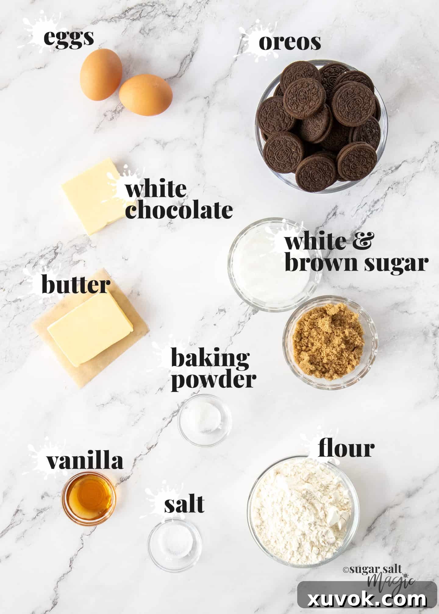 Various key ingredients laid out neatly for making delicious Oreo blondies on a pristine white marble surface, including Oreos, butter, flour, and sugars, ready for preparation.