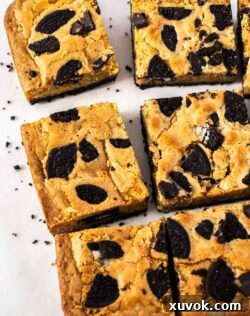 Top-down view of six delectable Oreo blondies arranged neatly on a sheet of baking paper, highlighting their fudgy centers and crunchy cookie pieces, ready to be enjoyed.