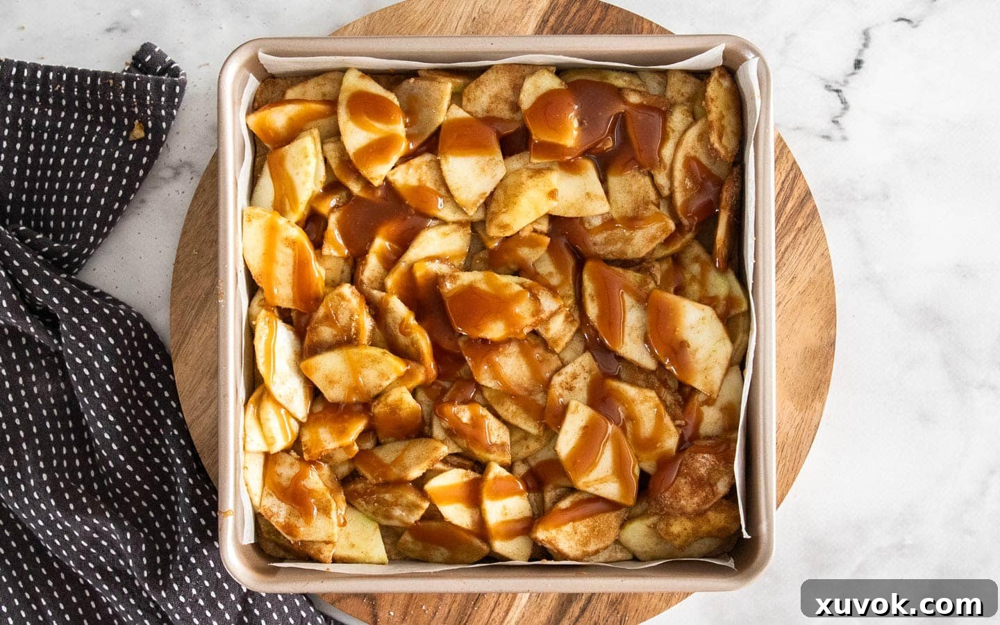 Spiced apple slices layered over the shortbread base in the pan, drizzled with luscious caramel sauce.