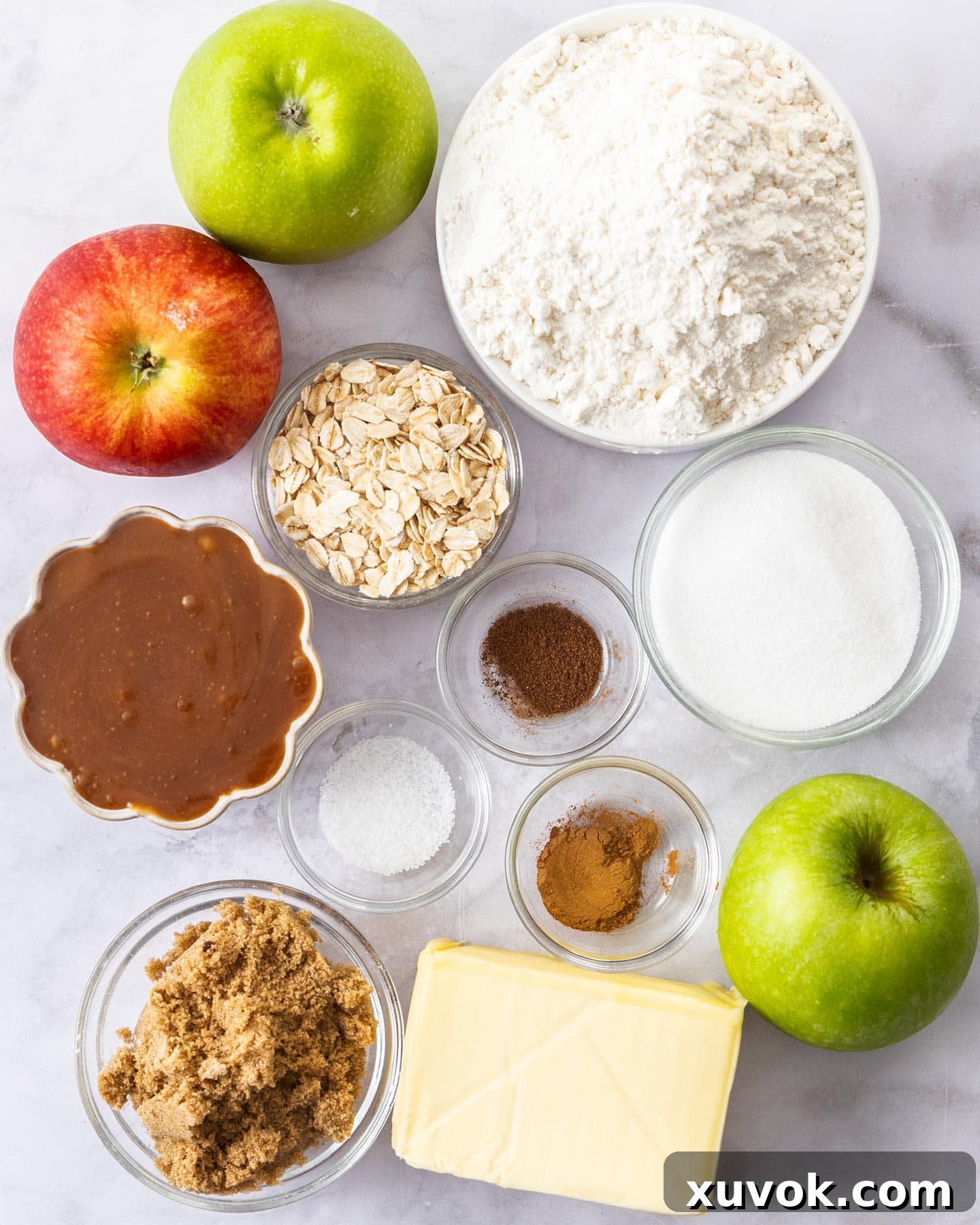 A selection of fresh ingredients laid out on a marble surface, ready for making salted caramel apple pie bars.
