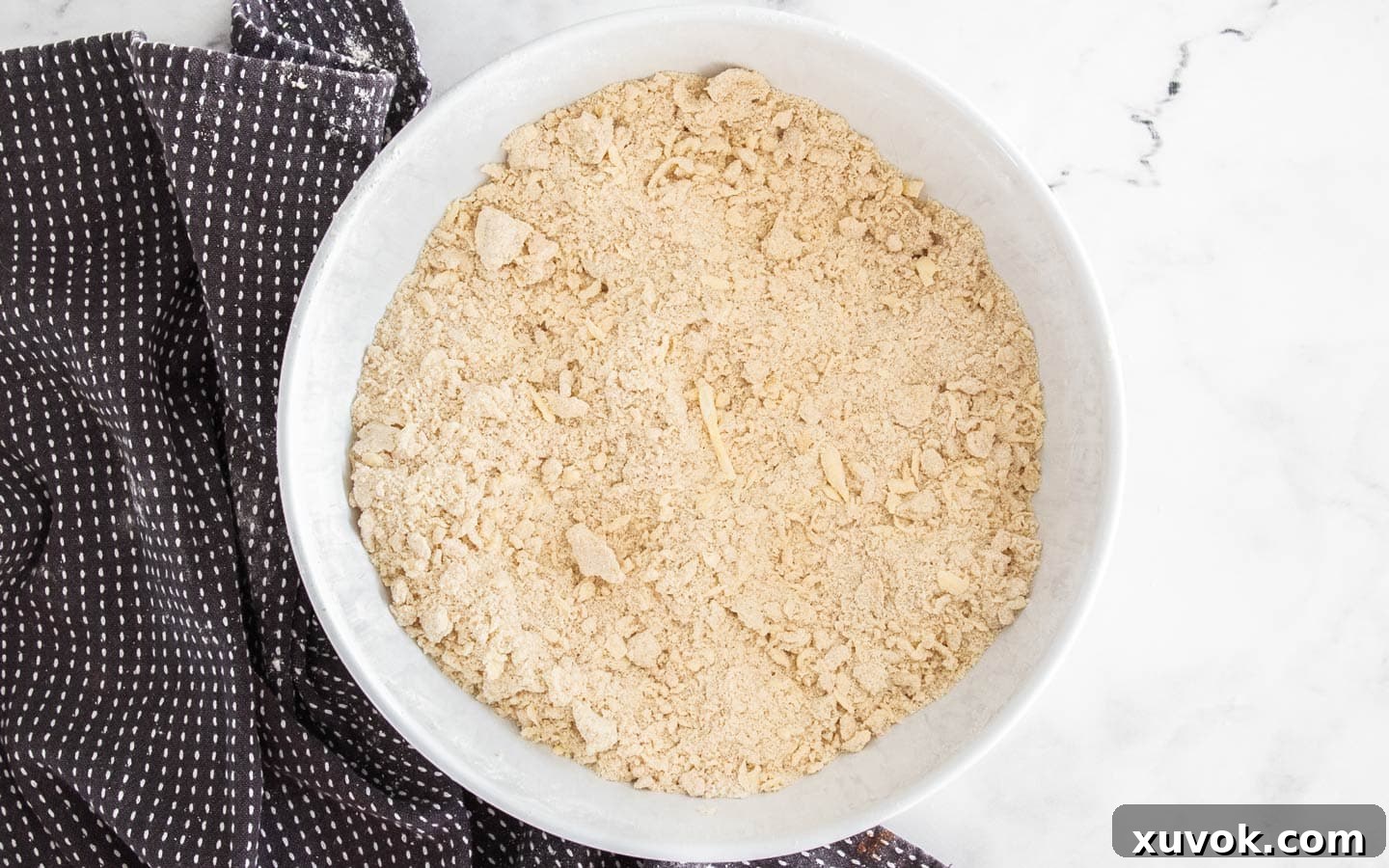 The butter has been successfully worked into the dry ingredients, resembling coarse crumbs in a mixing bowl.