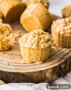 A coffee muffin on a board with glaze dribbling down the side.