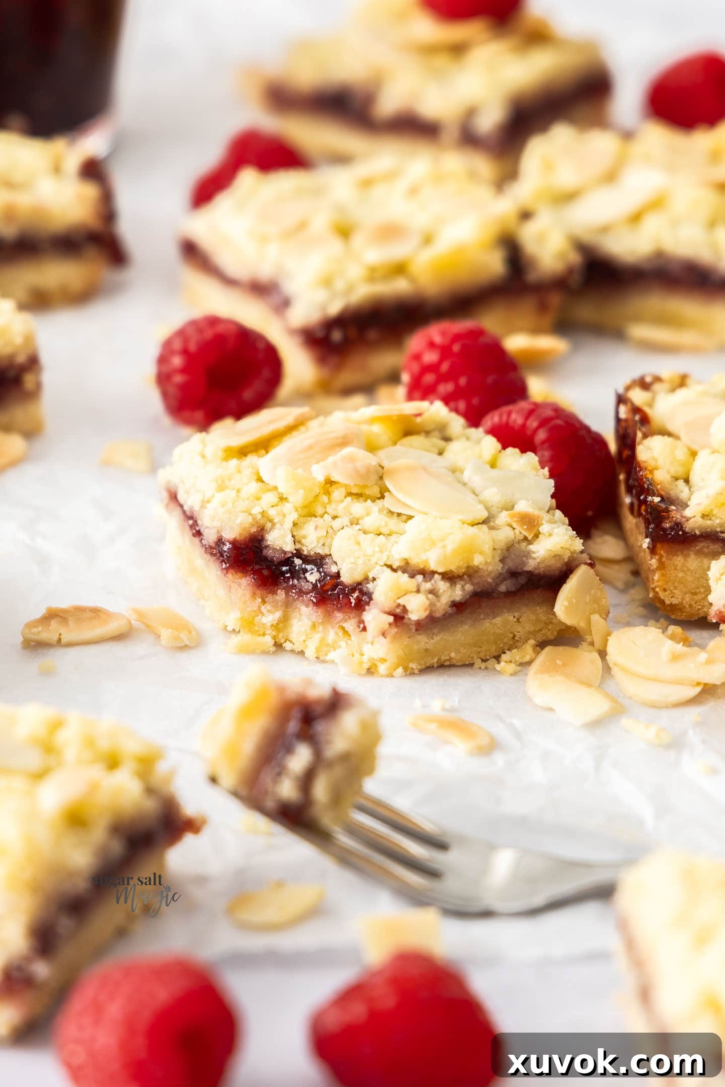 A single raspberry shortbread bar with a forkful cut away, revealing the layers.