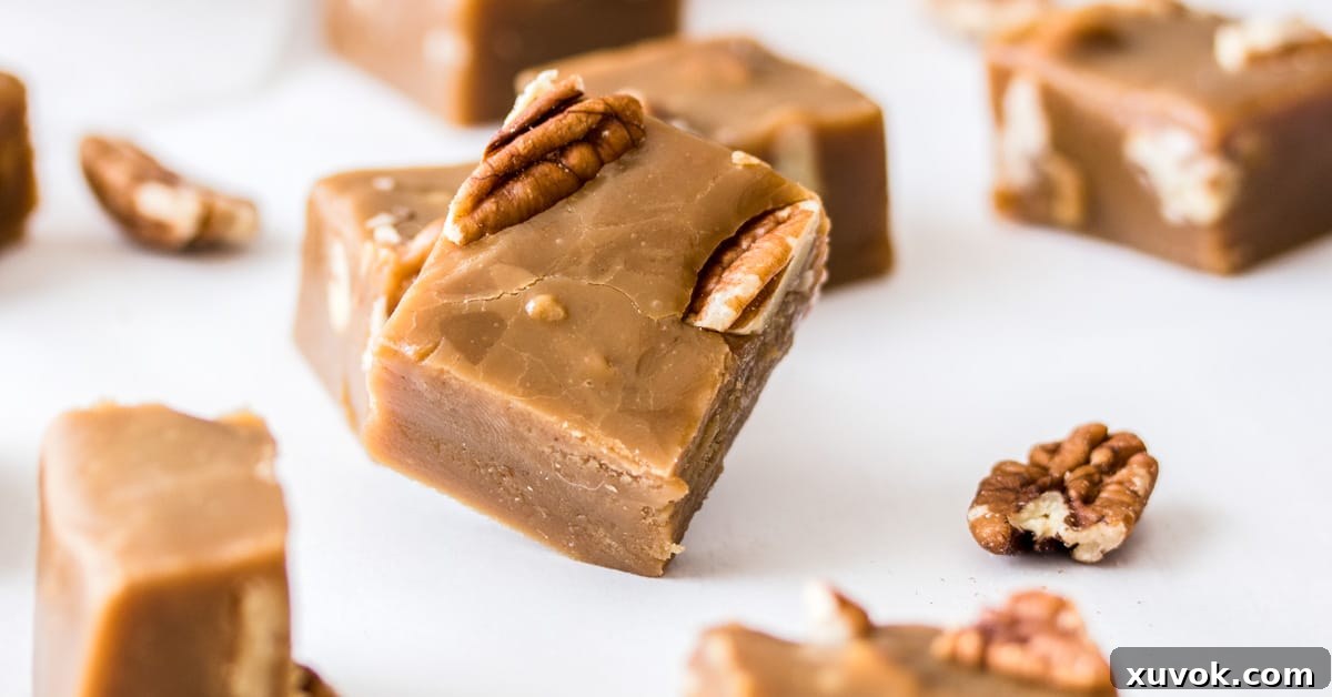 Squares of pecan butterscotch fudge on a white benchtop with some scattered pecans