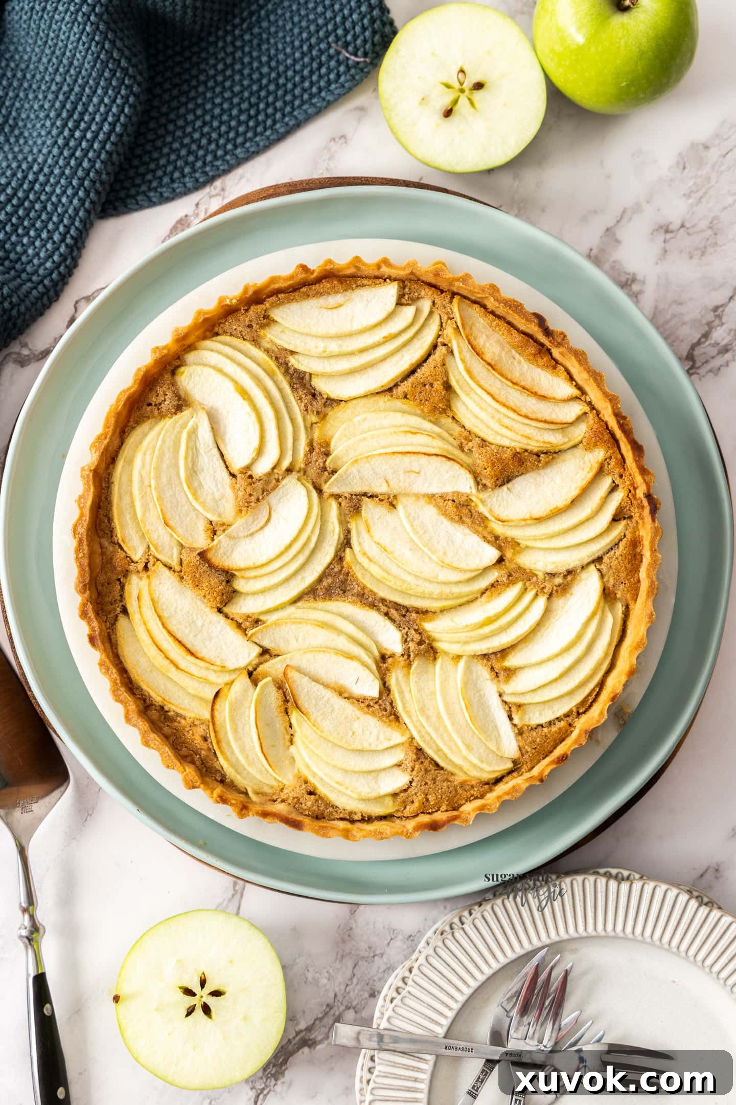 Top down view of a full apple frangipane tart, showcasing its beautiful golden crust and perfectly arranged apple slices.