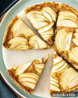 Apple frangipane tart cut into slices, beautifully presented and ready to serve.