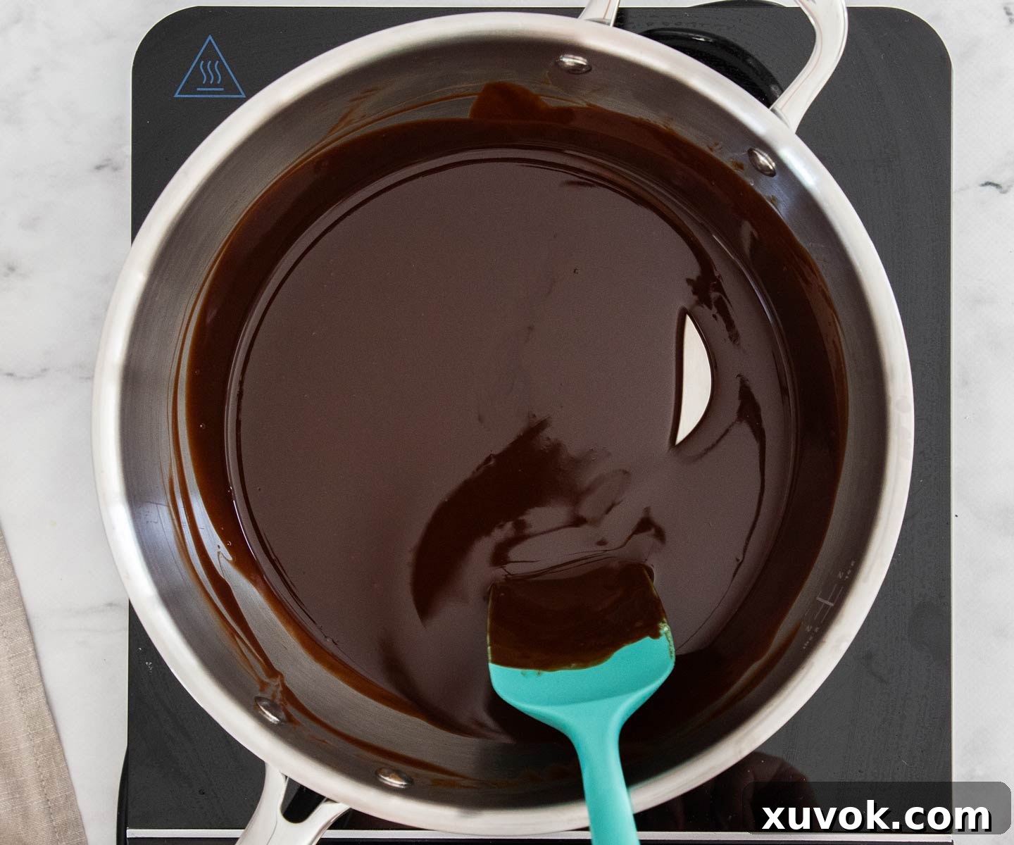 Chocolate and butter melted together into a smooth, glossy mixture in a saucepan.